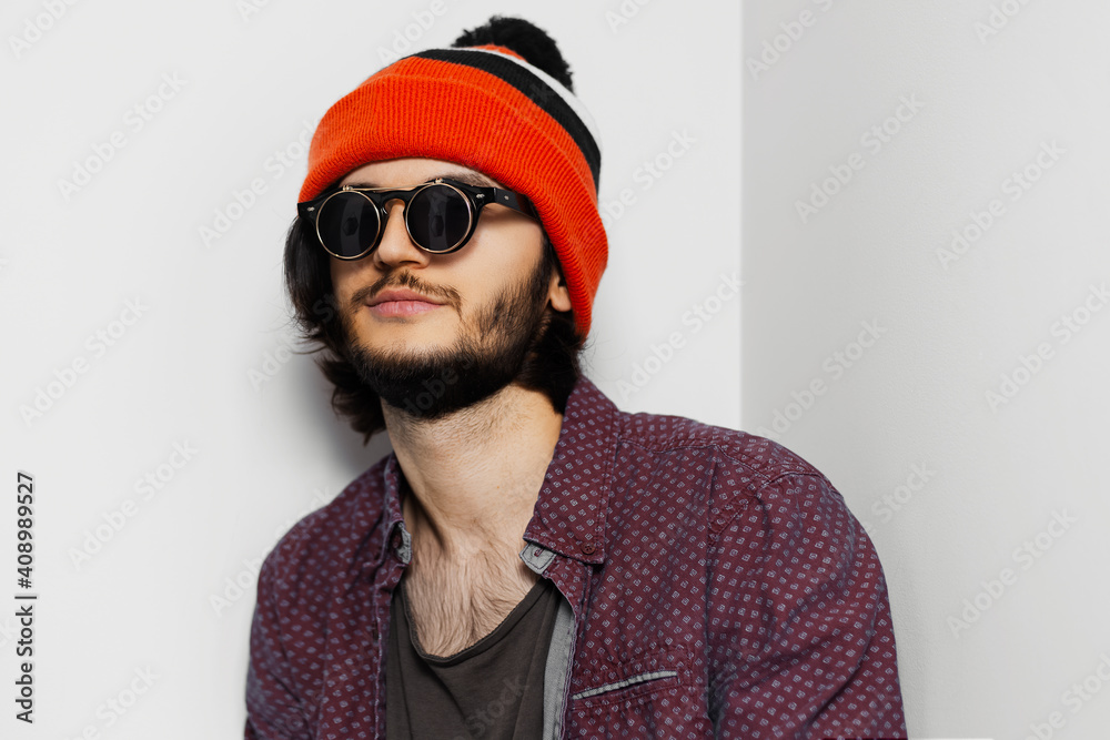 Studio portrait of young guy wearing round sunglasses and orange hat on white background. Studio portrait of young guy wearing round sunglasses and orange hat on white background.