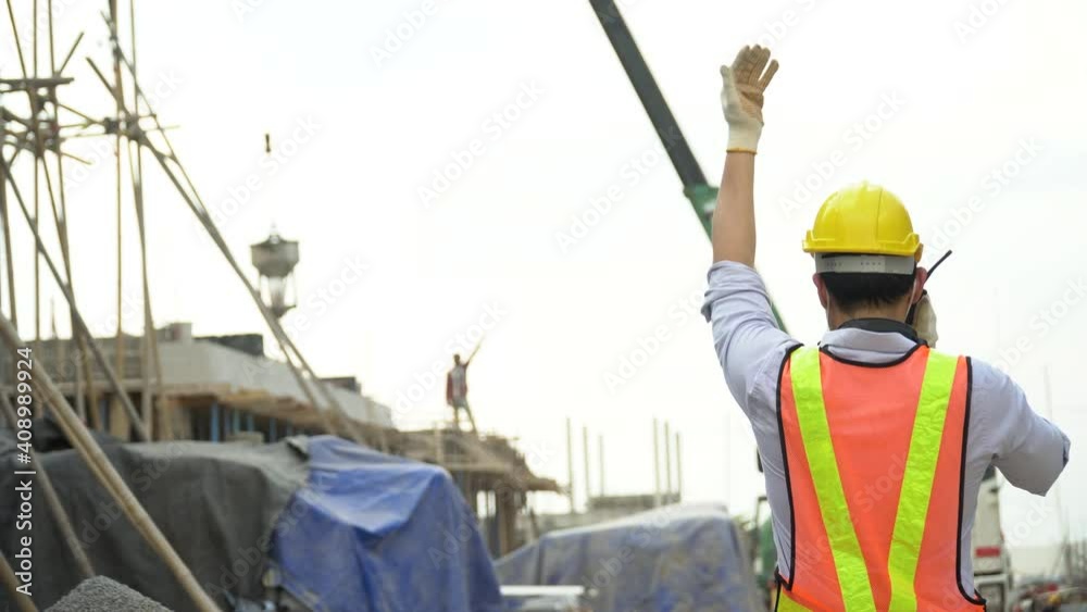 asian asian foreman in hard hat talking by walkie talkie control crane and concrete bucket Pouring cement with worker outdoors on construction site. contractor using radio operation in industry asian asian foreman in hard hat talking by walkie talkie control crane and concrete bucket Pouring cement with worker outdoors on construction site. contractor using radio operation in industry