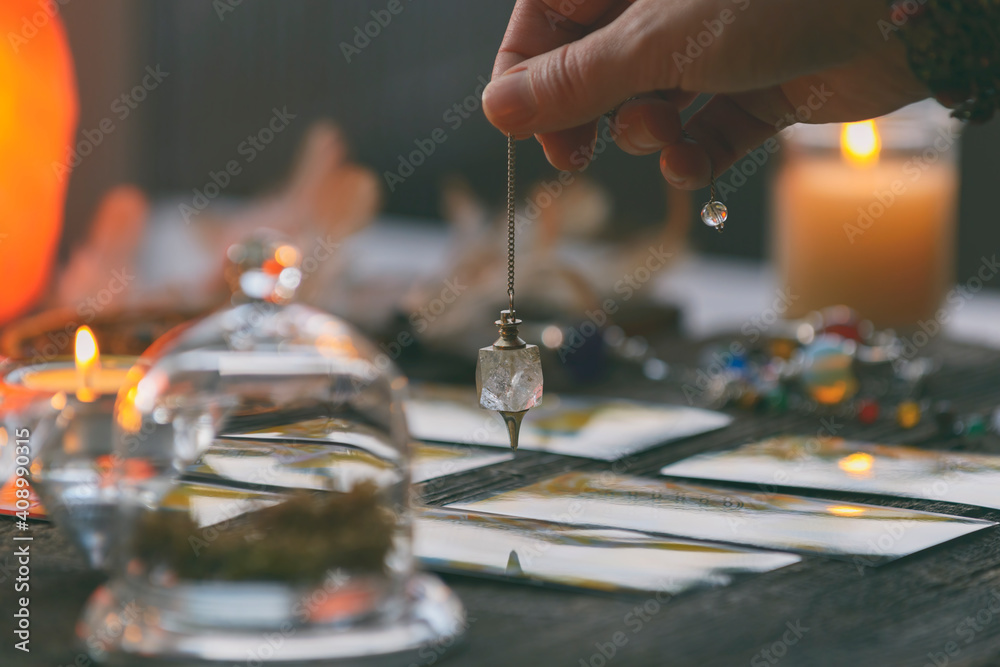 Obraz premium Hand with pendulum over tarot cards