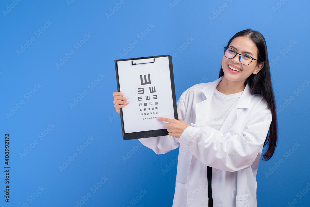 Young female ophthalmologist with glasses holding eye chart over blue background studio, healthcare concept Young female ophthalmologist with glasses holding eye chart over blue background studio, healthcare concept