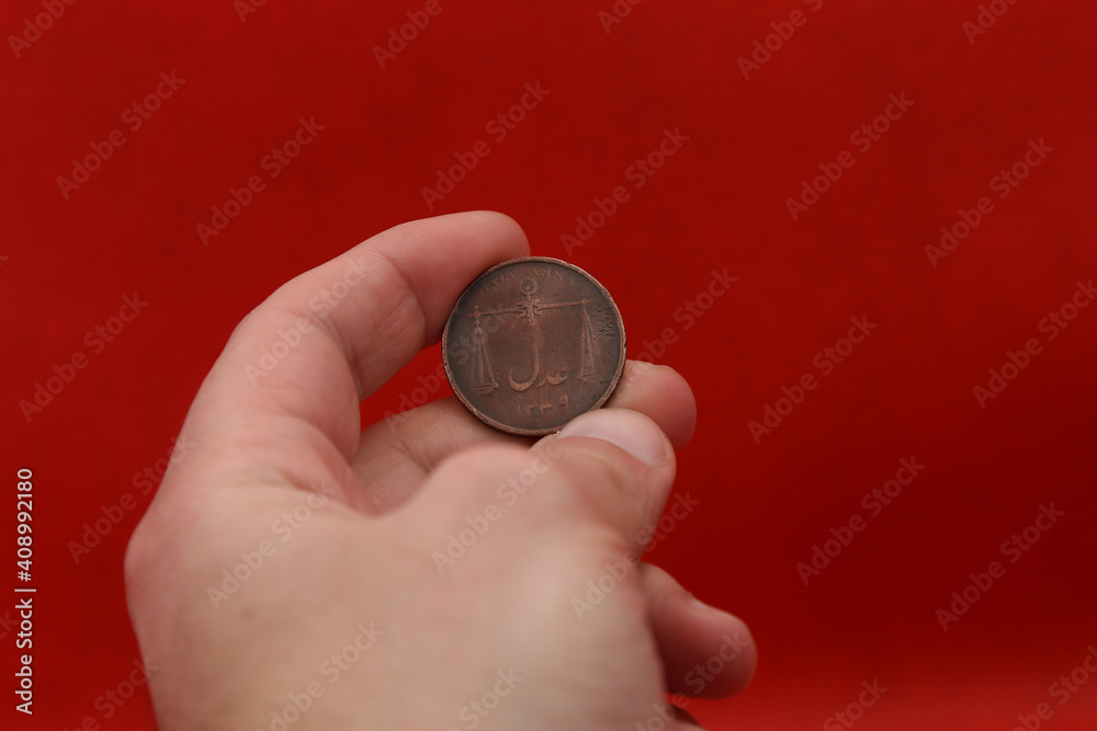 Old copper coin of colonial India half anna in hand on red background Old copper coin of colonial India half anna in hand on red background
