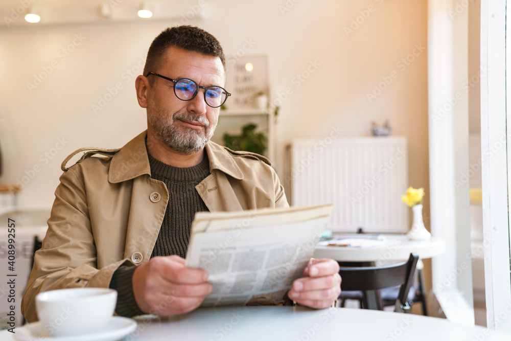 Handsome businessman reading newspaper in cafe Handsome businessman reading newspaper in cafe