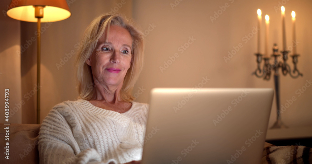 Portrait of smiling mature woman sitting on couch using laptop and having virtual conference Portrait of smiling mature woman sitting on couch using laptop and having virtual conference