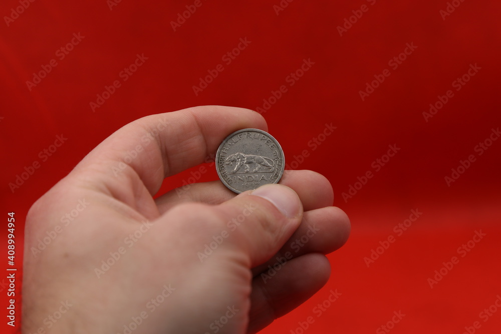 Old coin of India in hand on red background Old coin of India in hand on red background