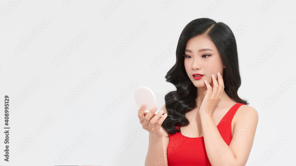 A woman is holding a pink small mirror in her hands. A woman is holding a pink small mirror in her hands.
