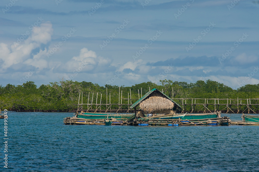 A Fish pen with a small hut off the coast of Tubigon, Bohol, Philippines.  An enclosure filled with Tilapia or Bangus. Cage and Pen fish farming  industry. Photos