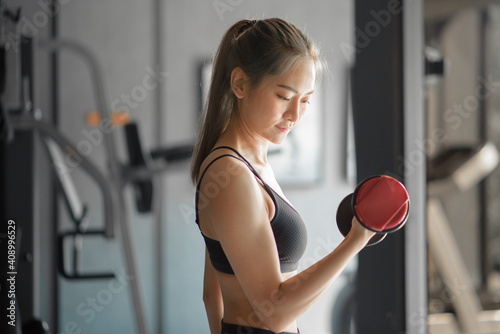 Beautiful young woman in sportswear exercising with dumbbells at the gym, concept of healthy lifestyle, sports, training, wellness, and sport