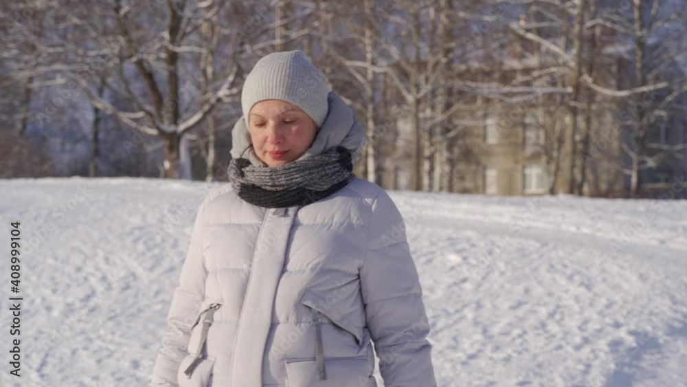 pregnant woman in winter warm jacket with hood walks in snowy park on cold sunny day. High quality 4k footage pregnant woman in winter warm jacket with hood walks in snowy park on cold sunny day. High quality 4k footage