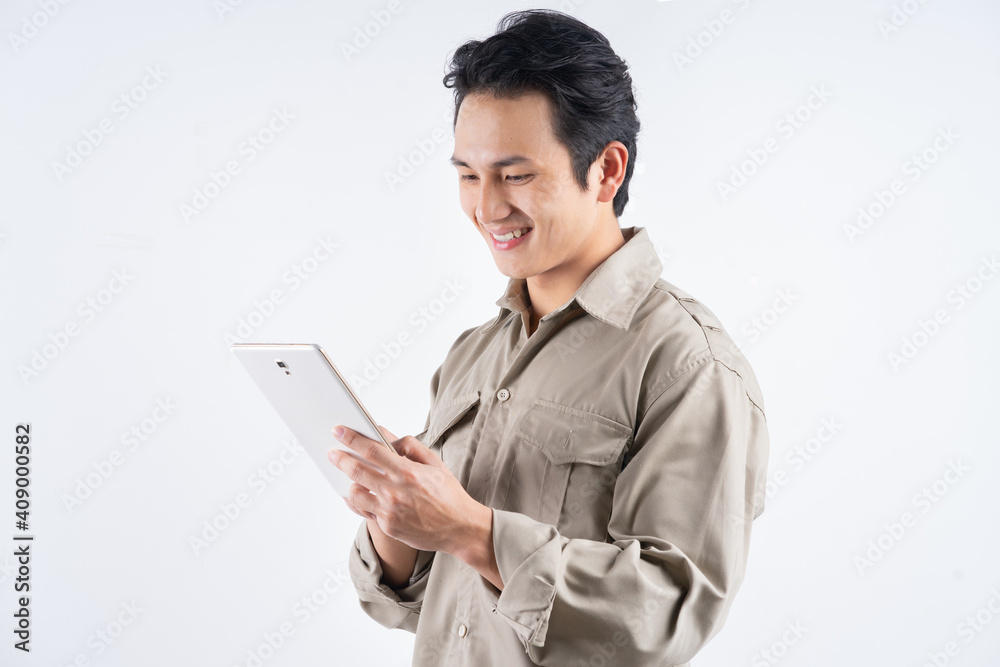 Good looking young mechanic in overalls using a tablet computer for work and smiling Good looking young mechanic in overalls using a tablet computer for work and smiling