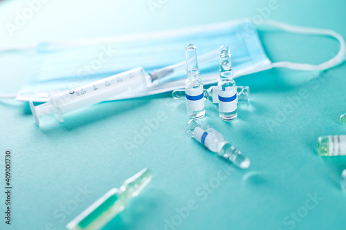 Ampoules with Covid-19 vaccine on blue background. Vaccination concept.
