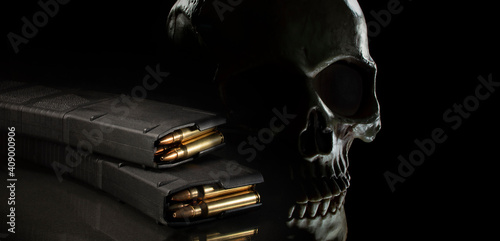 Quadro su tela Human skull on a dark background with loaded thirty round magazines for an AR-15