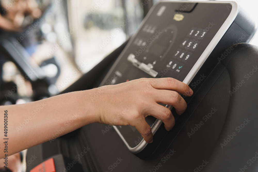 Woman changing settings on a treadmill in a gym Woman changing settings on a treadmill in a gym