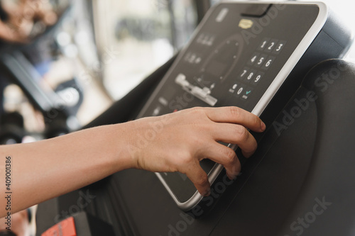 Woman changing settings on a treadmill in a gym