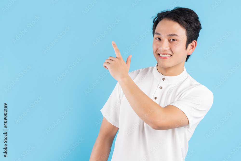 The young man standing on his side pointed his hand to the side with a cheerful expression The young man standing on his side pointed his hand to the side with a cheerful expression