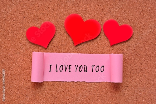 I love you too label on Torn paper with heart shape on wooden background