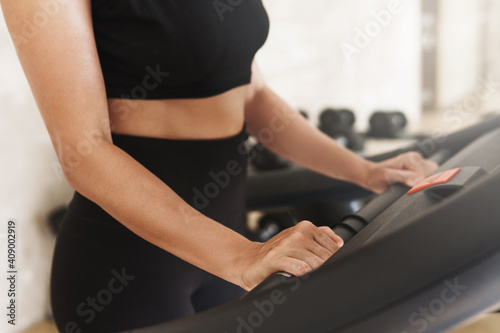 Female hands holding handles of treadmill during fitness workout