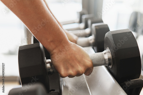 Female hands and dumbbells on the rack in gym