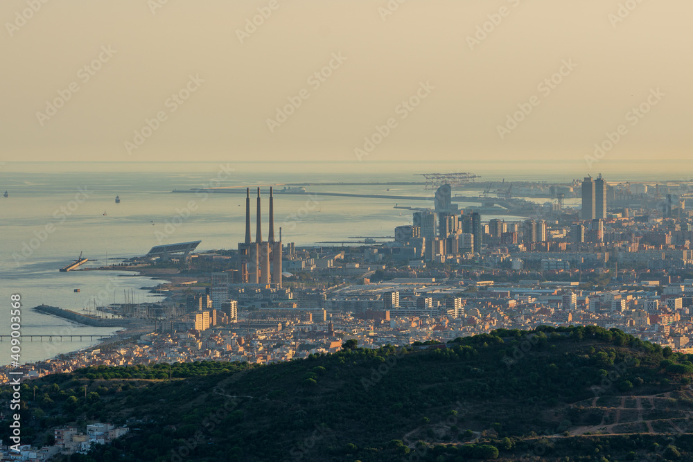 Panoramic view of the entire city of Barcelona and its surroundings. During sunset one day in late summer. We can see the Mediterranean sea completely flat.