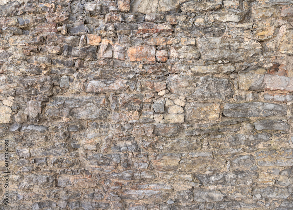 Alte graue Mauer aus vielen, unterschiedlich großen Natursteinen