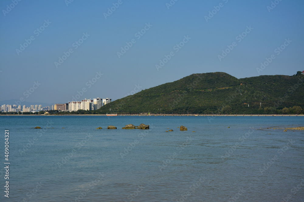 blue sea view with mountains and buildings under clear sky in sunny day