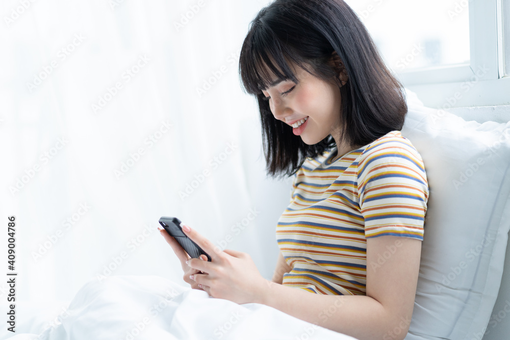 Beautiful Asian woman using phone on bed in bedroom Beautiful Asian woman using phone on bed in bedroom