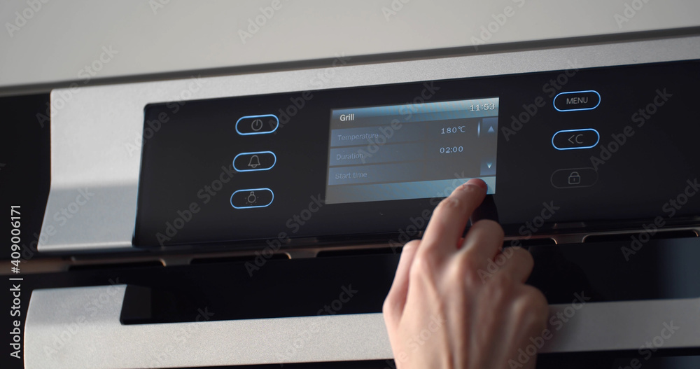 Female finger regulating temperature and time on touch panel of oven