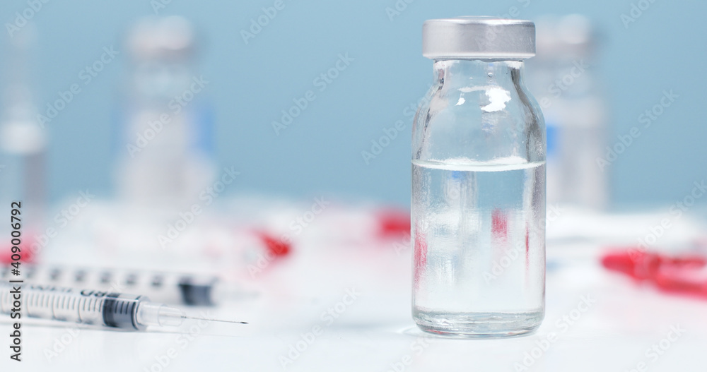Medical bottle, vials, syringes injection for vaccination on blue background with copy space Medical bottle, vials, syringes injection for vaccination on blue background with copy space