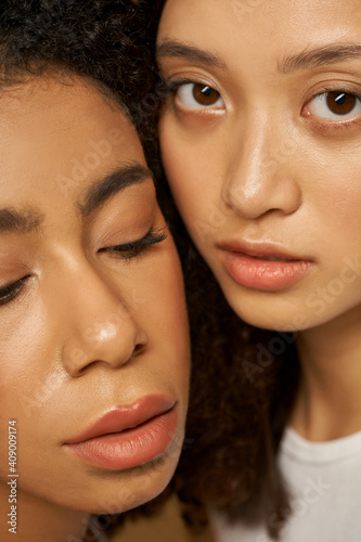 Face closeup of two beautiful mixed race young women with perfect glowing skin posing together