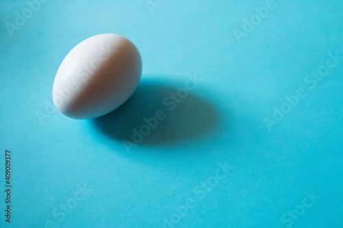Easter concept. One white egg isolated on color blue pastel background.