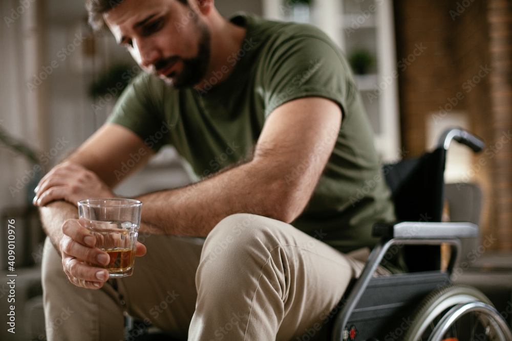 Depression man in wheelchair drinking alcohol at home. Lonely man is addicted of alcohol..