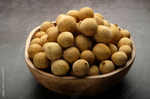 Longkong  tropical fruit in a wooden bowl on dark background.