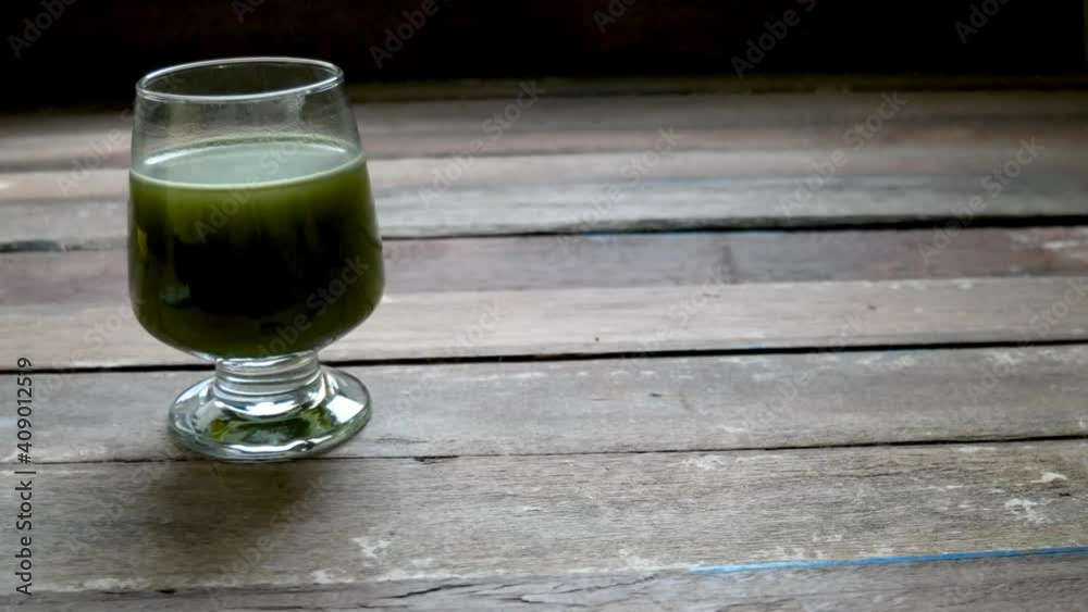 Wine glasses has hot Matcha green tea,and has collagen powder on top,on old wood table top,natural dimly light,selective focus.Concept of relaxation with healthy tea. Wine glasses has hot Matcha green tea,and has collagen powder on top,on old wood table top,natural dimly light,selective focus.Concept of relaxation with healthy tea.