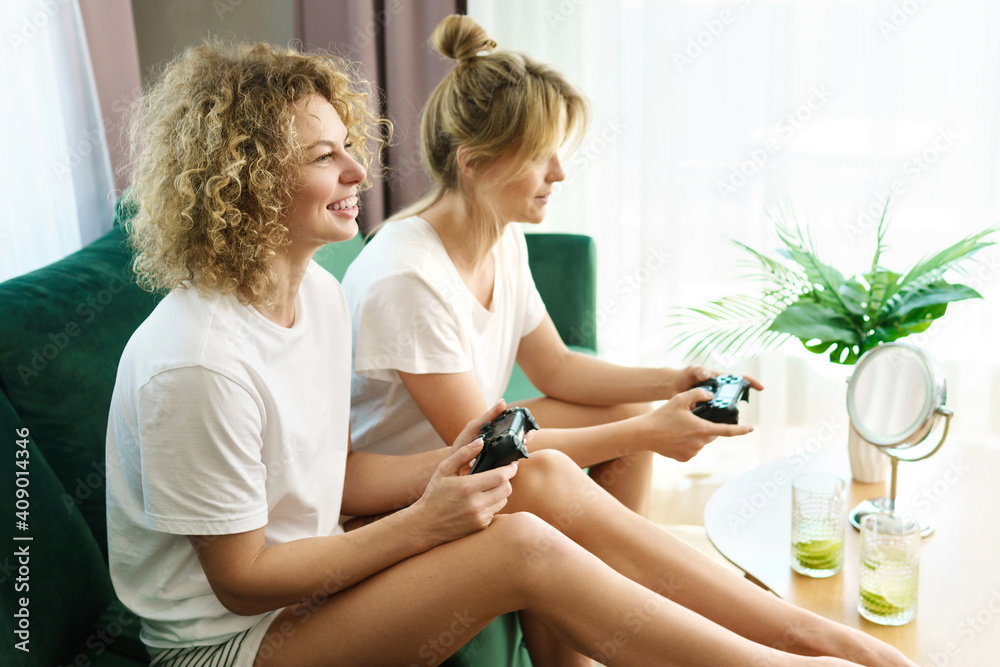 Fototapeta premium Two beautiful girls playing video game console in living room