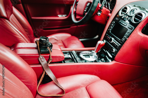 Red luxury car interior - dashboard with gauges, steering wheel and shift lever. Modern car inside. Comfortable leather red seats. Details. Camera in the car.