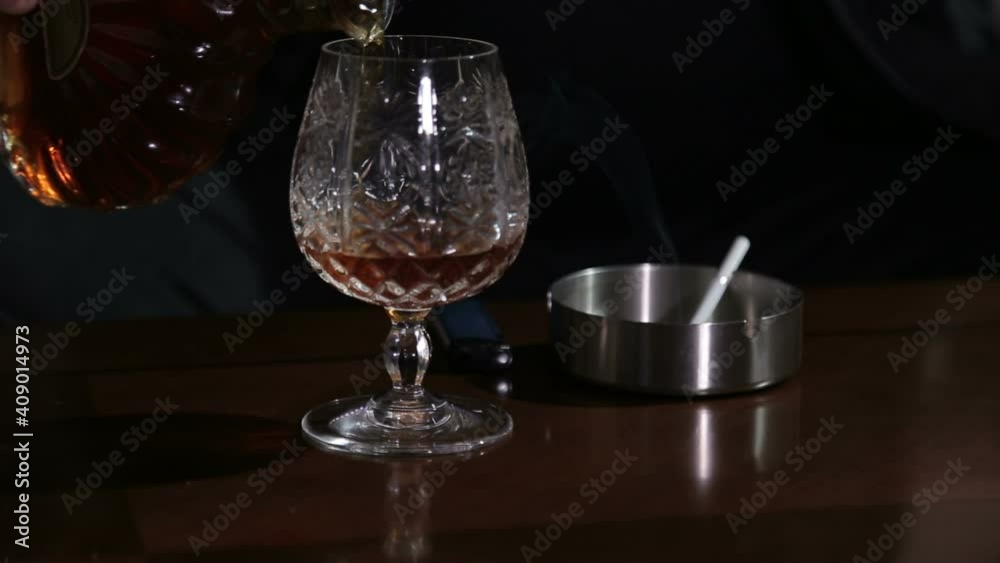 Man in dark pouring himself whiskey, drinking it and lighting a cigarette. Man in dark pouring himself whiskey, drinking it and lighting a cigarette.