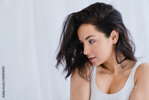 Side view portrait of a young attractive girl with gorgeous hair in the bedroom