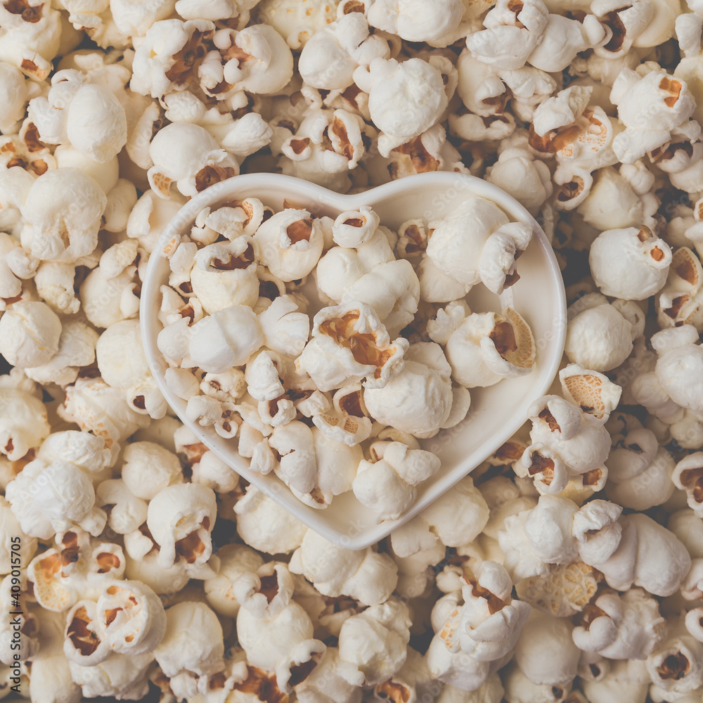 Some homemade Popcorn as detailed close-up shot, heart shaped bowl, top view. Instagram matte filter.