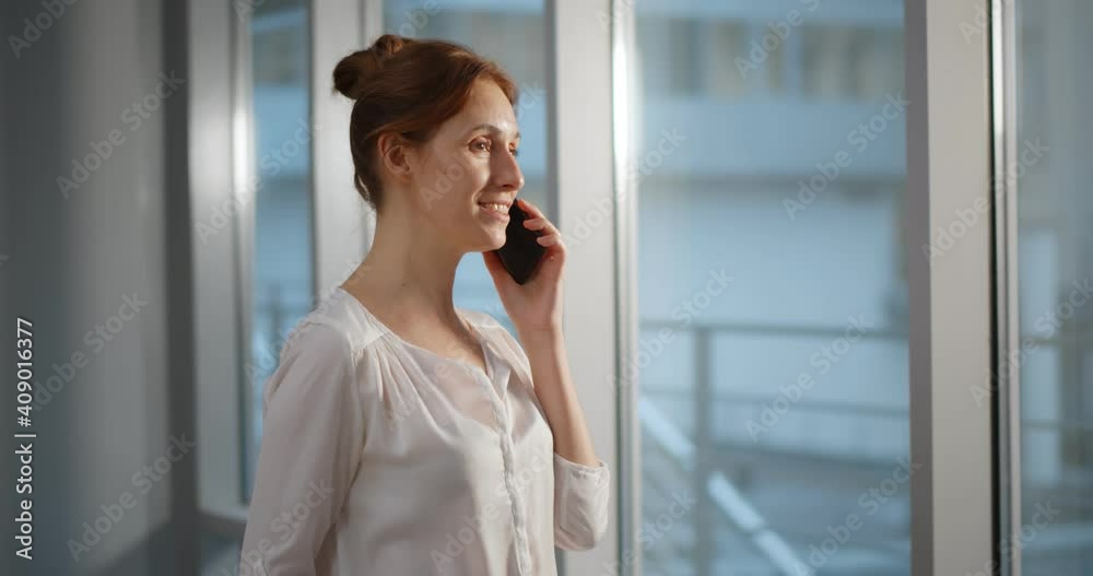 Businesswoman talking on phone in modern office with panoramic windows Businesswoman talking on phone in modern office with panoramic windows