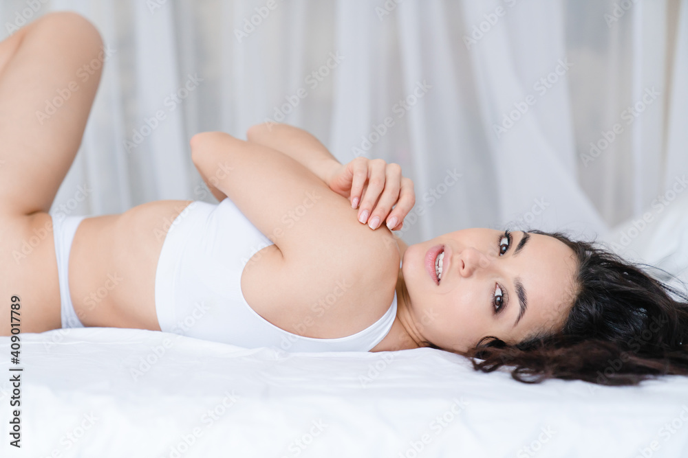 Pretty passionate young girl lying on white bed linen in sexy lingerie Pretty passionate young girl lying on white bed linen in sexy lingerie