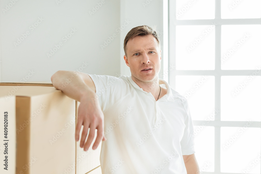 pensive young man standing near cardboard boxes pensive young man standing near cardboard boxes