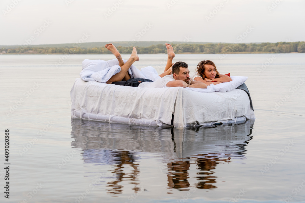 Beautiful couple relaxing on the floating bed in lake