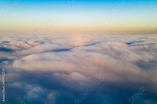 Striking aerial view of the sunset sky with the clouds below us. The shadows projected from the Sun passing through the clouds create a dramatical landscape view. Flying above the clouds in the search © abriendomundo