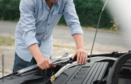 Man inspecting and servicing the engine, bonnet, safety test tool before the customer is on a long trip.