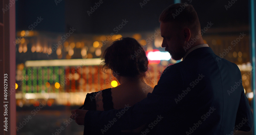 Back view of handsome man unzipping dress of beautiful woman standing together near panoramic window Back view of handsome man unzipping dress of beautiful woman standing together near panoramic window