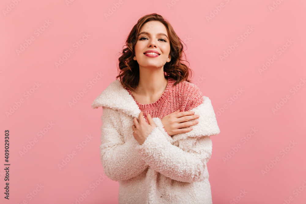 Romantic young woman in coat looking at camera. Front view of glad female model posing on pink background. Romantic young woman in coat looking at camera. Front view of glad female model posing on pink background.