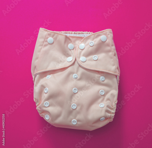 Reusable cloth baby diaper. Eco friendly nappy on pink background.