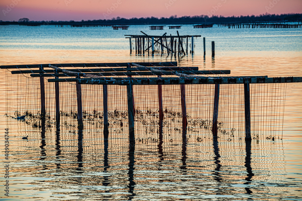 Breathtaking sunset in Po Delta with Stilts for Shell fishing, Italy