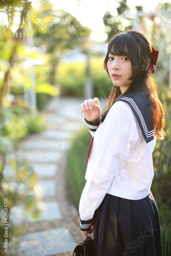 Asian school girl walk and looking with flower garden background