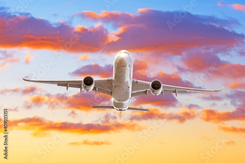 Passenger jet plane take off from airport runway with beautiful sky clouds light of sun rising behind.