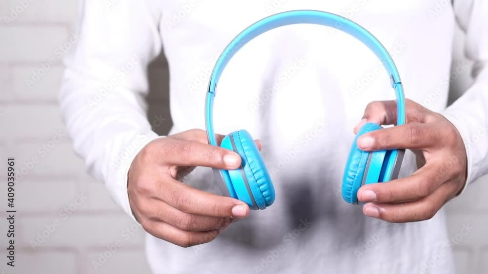 Man hand holding headphone on blue background Man hand holding headphone on blue background